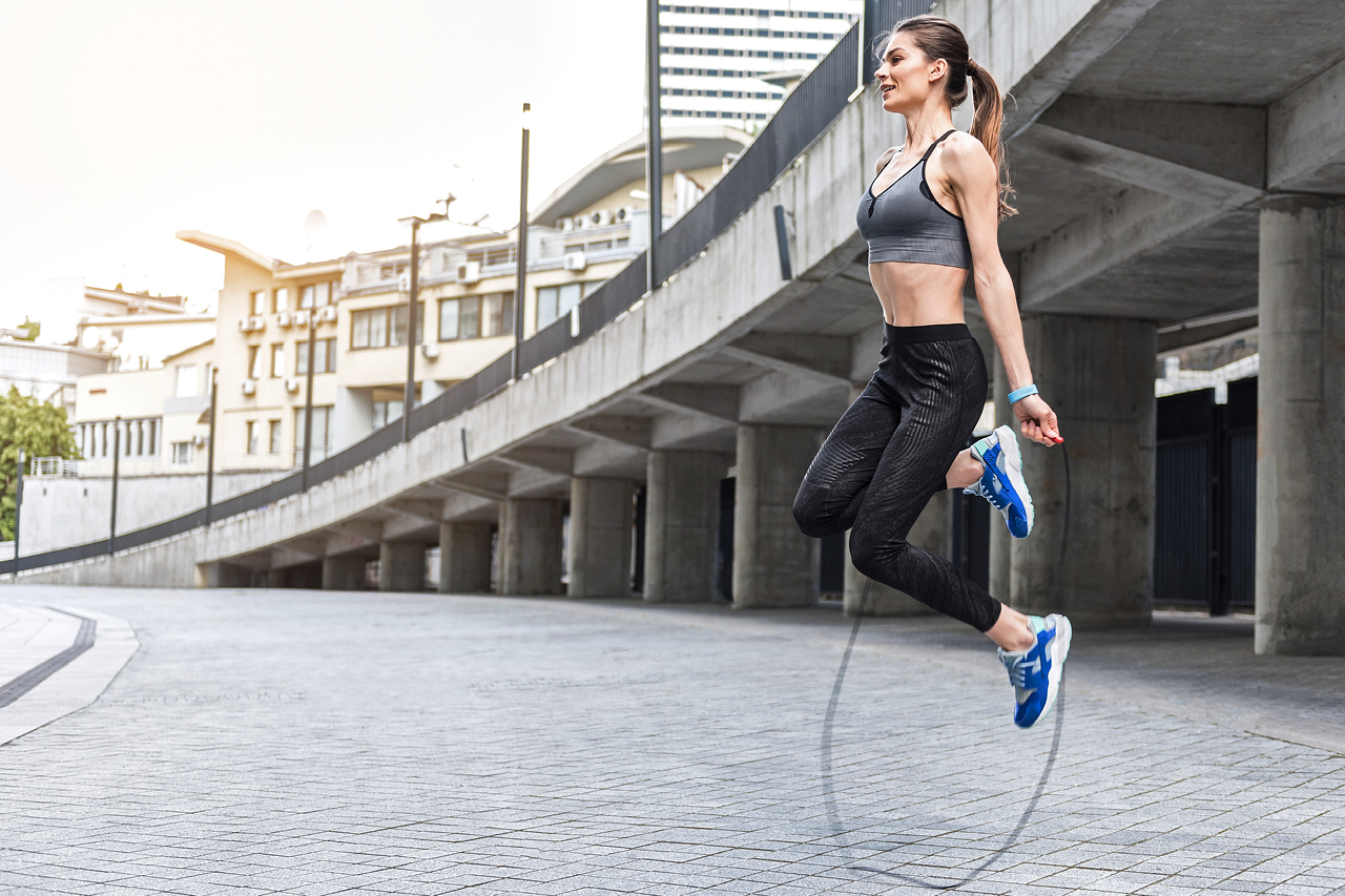 Young fit woman exercising outside with a jump rope