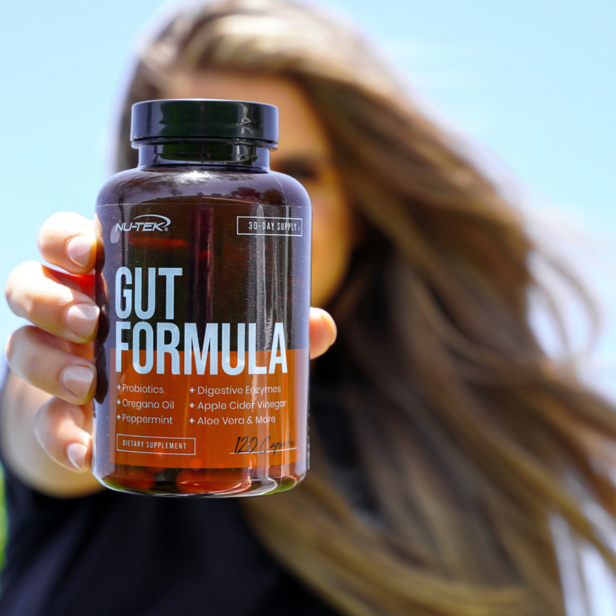 Woman holding a bottle of Gut Formula capsules