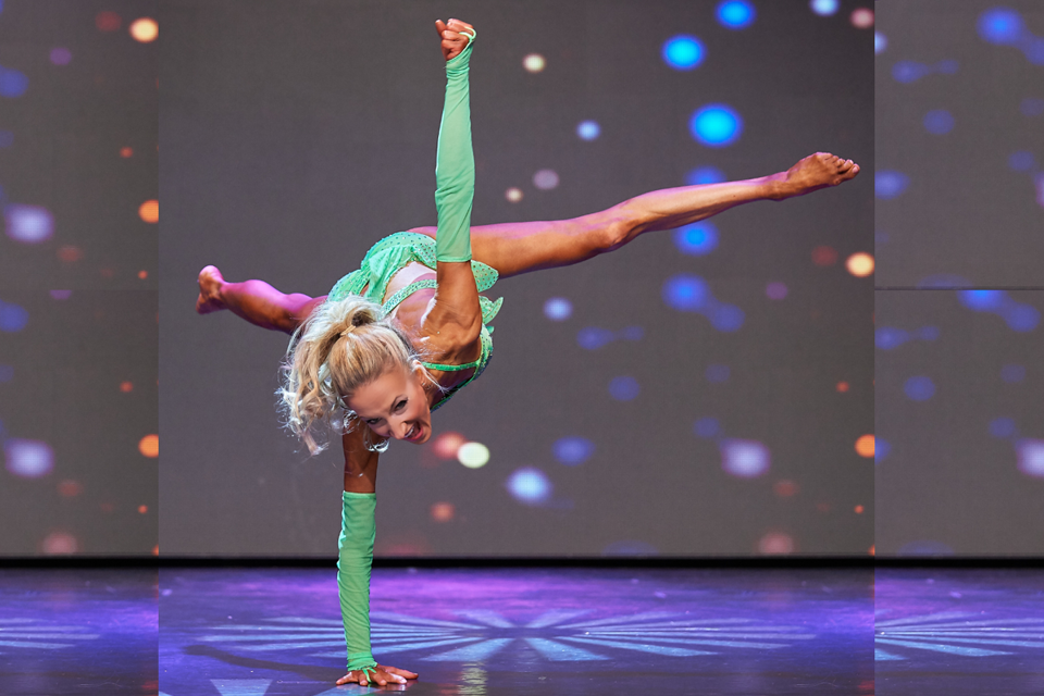 Meredith Butulis does a one-handed handstand on stage during a recent fitness competition