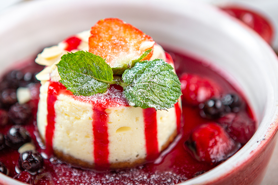 Mini cheesecake surrounded with raspberry sauce and berries