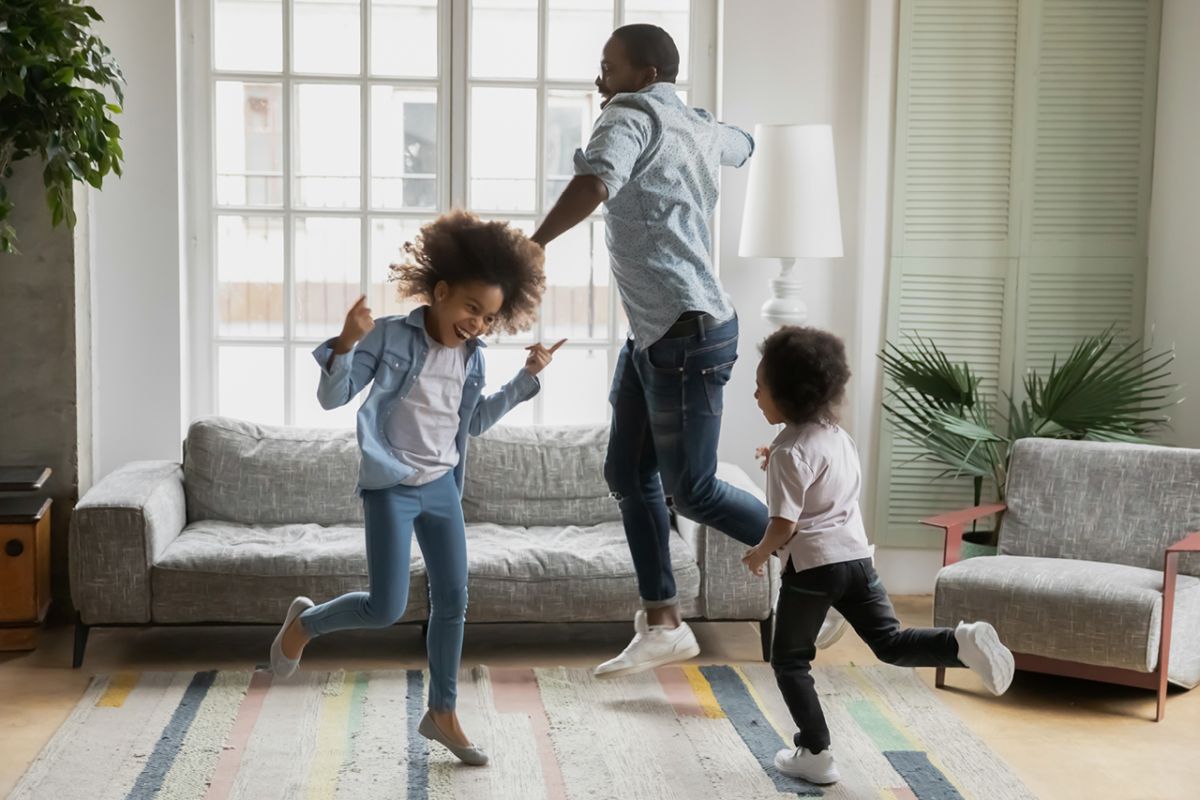 Father dancing and having fun with his daughters in the living room of their home