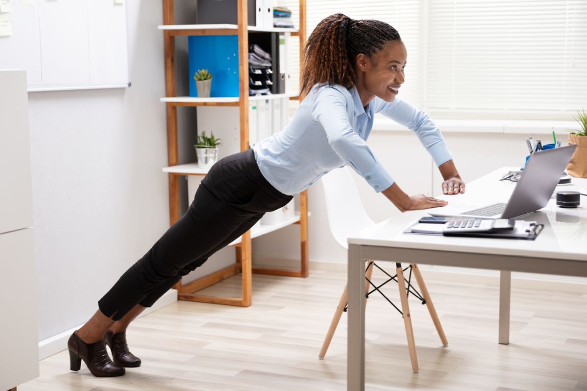 Woman performs a push-up off her desk in the office