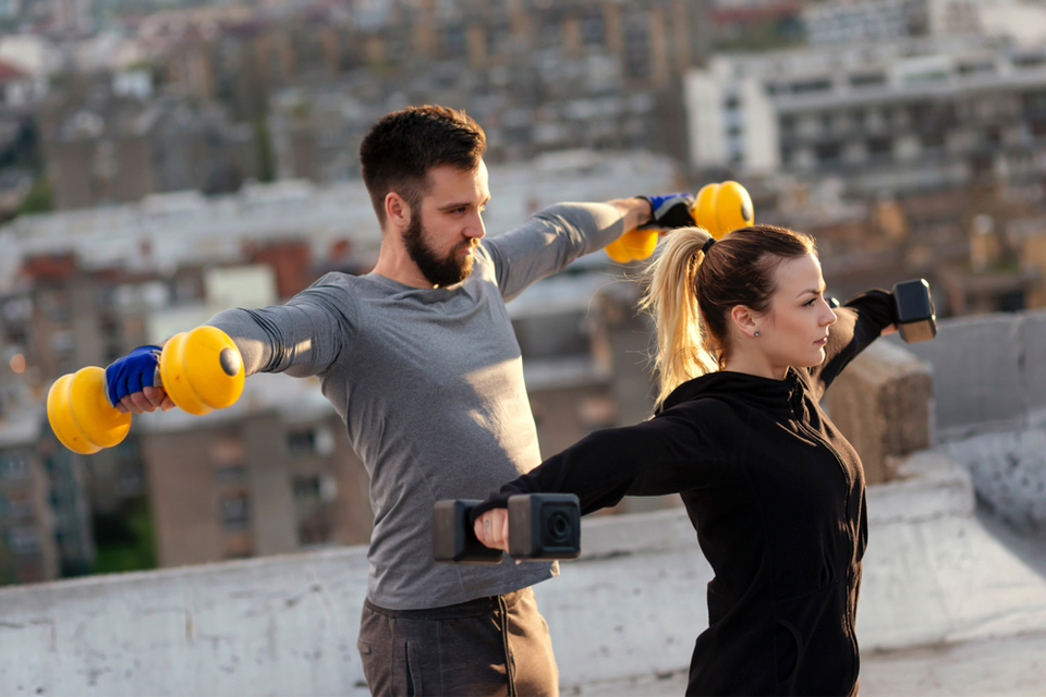 Woman and a man doing dumbbell lateral raises