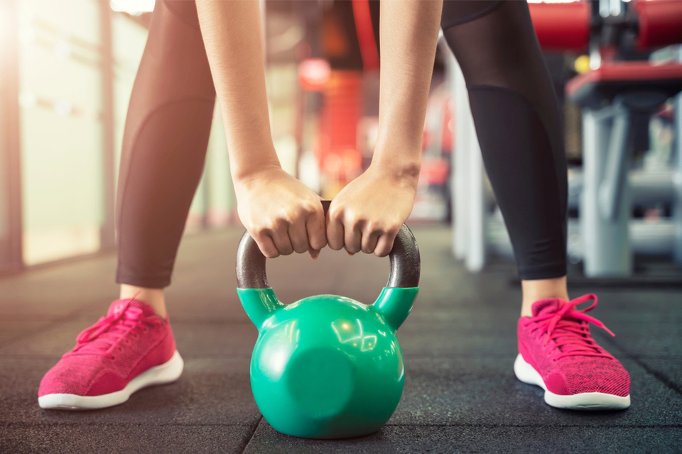 Close up of kettlebell on the floor with hands holding it