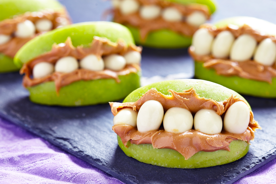 apple slices with peanut butter and yogurt covered peanuts to look like a mouth