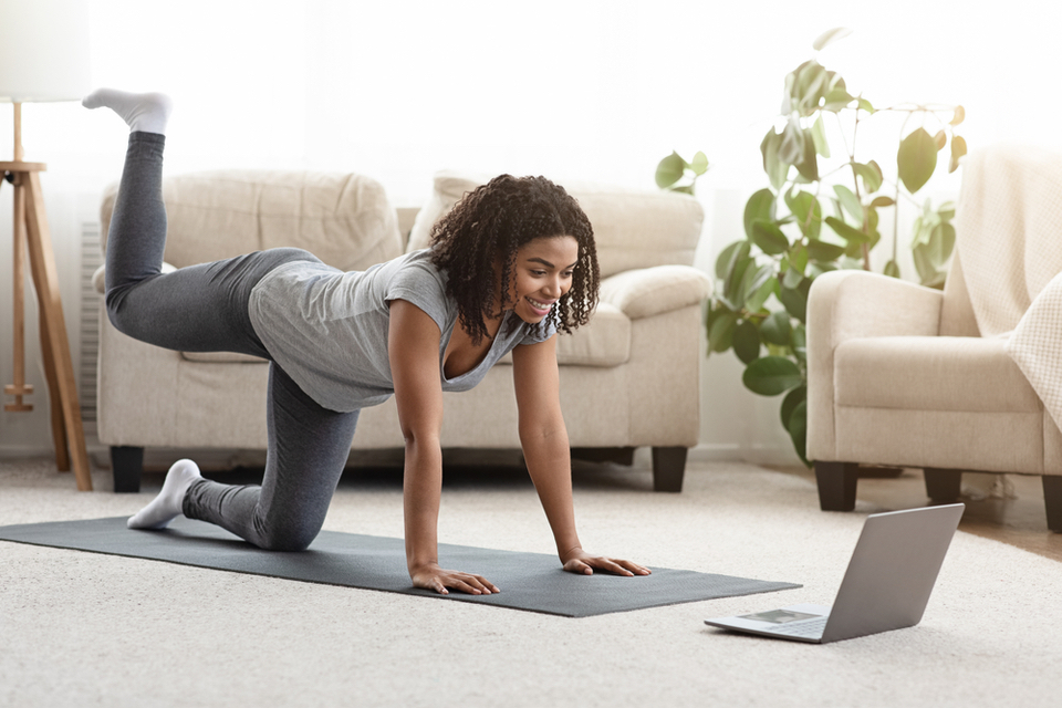 Woman working out in her living room watching her laptop