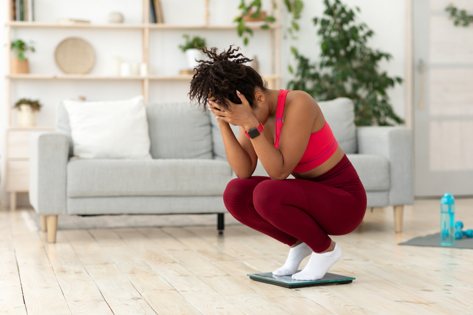 Upset woman crouched over scale