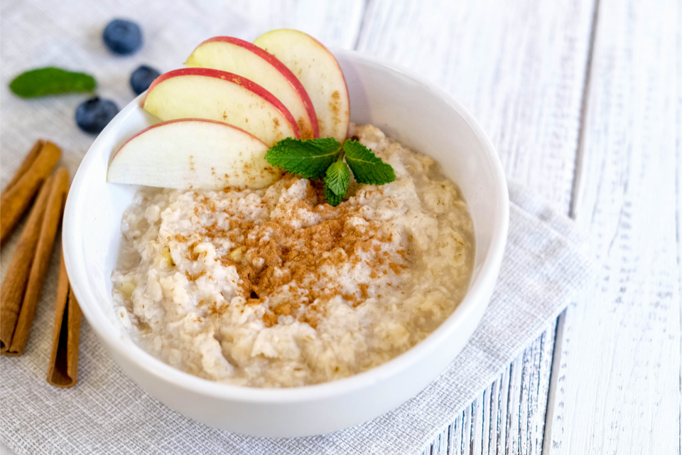 Bowl of oatmeal with apple slices and powdered cinnamon