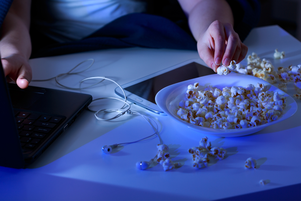 Person on computer eating popcorn