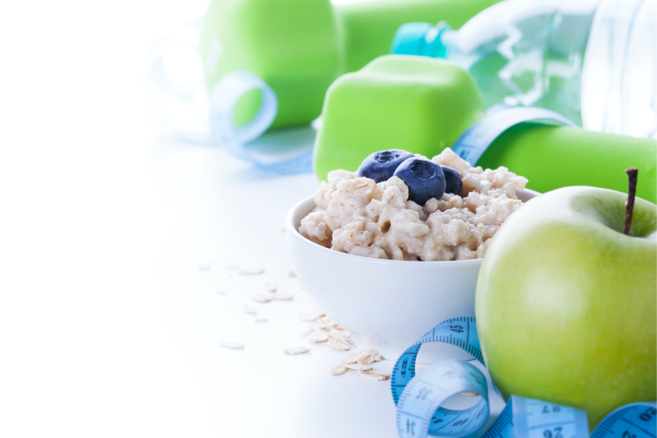 Bowl of oatmeal , a green apple and dumbbells 