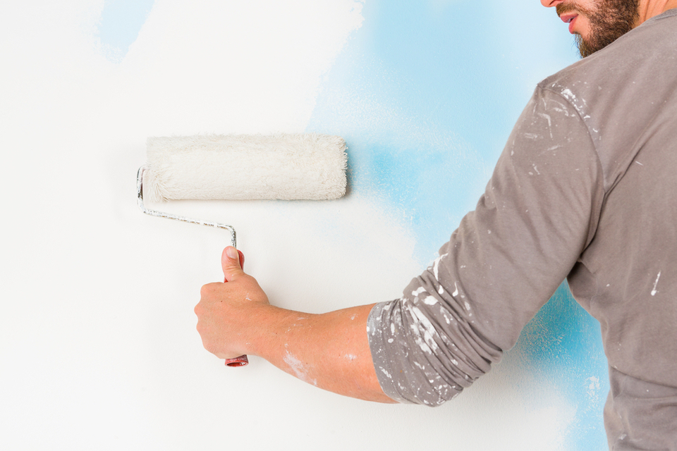 Close up of an arm painting a wall