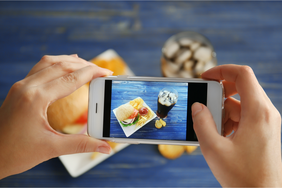 Close up of hands holding phone taking a photo of food