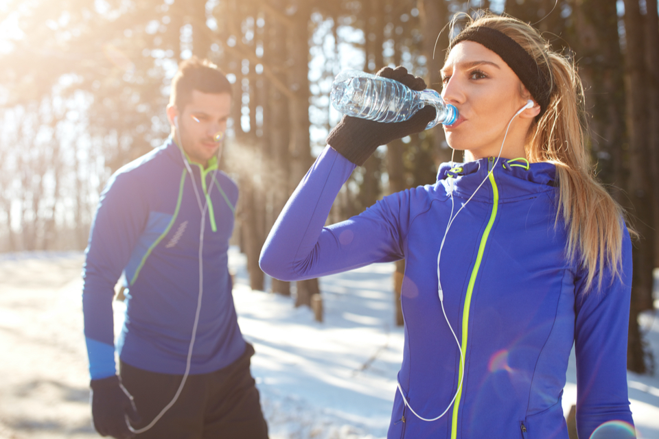 People drinking water on a snowy trail