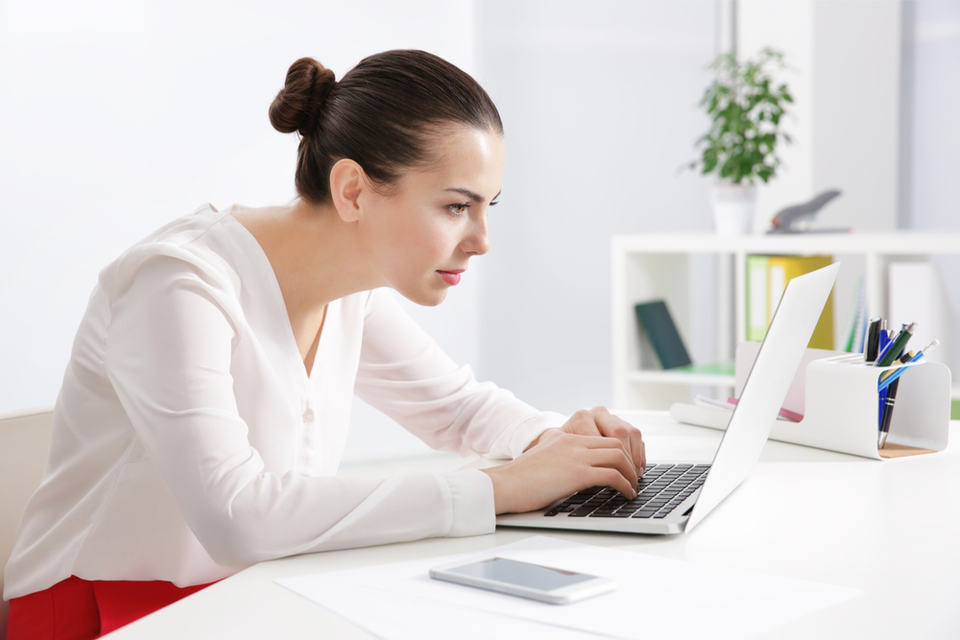 Woman hunched over working on her laptop