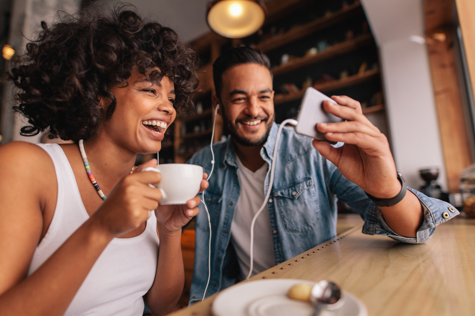 Man and woman laughing will starting at something in a phone