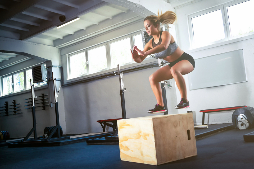 Woman mid air while doing box jumps