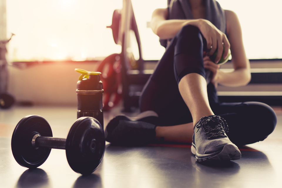 Person sitting on floor next to a dumbbell