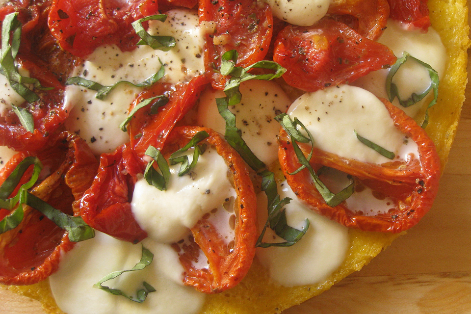 Close up of diced tomatoes and cheese on pizza bread