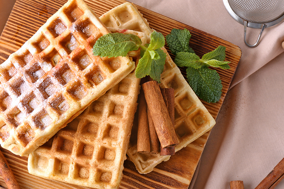 Waffles with powdered sugar and cinnamon sticks