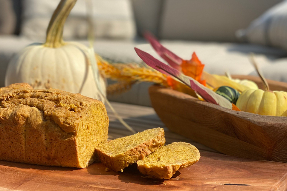 Sliced pumpkin bread surrounded by pumpkins