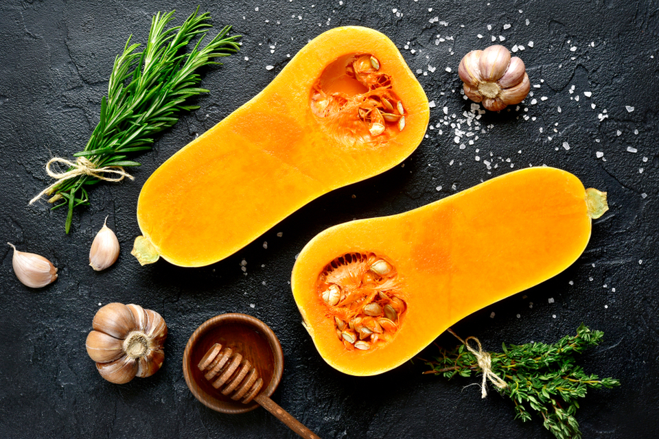 Overhead view of a squash cut in half surrounded by salt and herbs