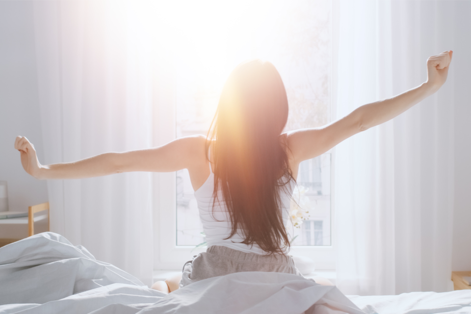 Woman stretching in front of window right out of bed