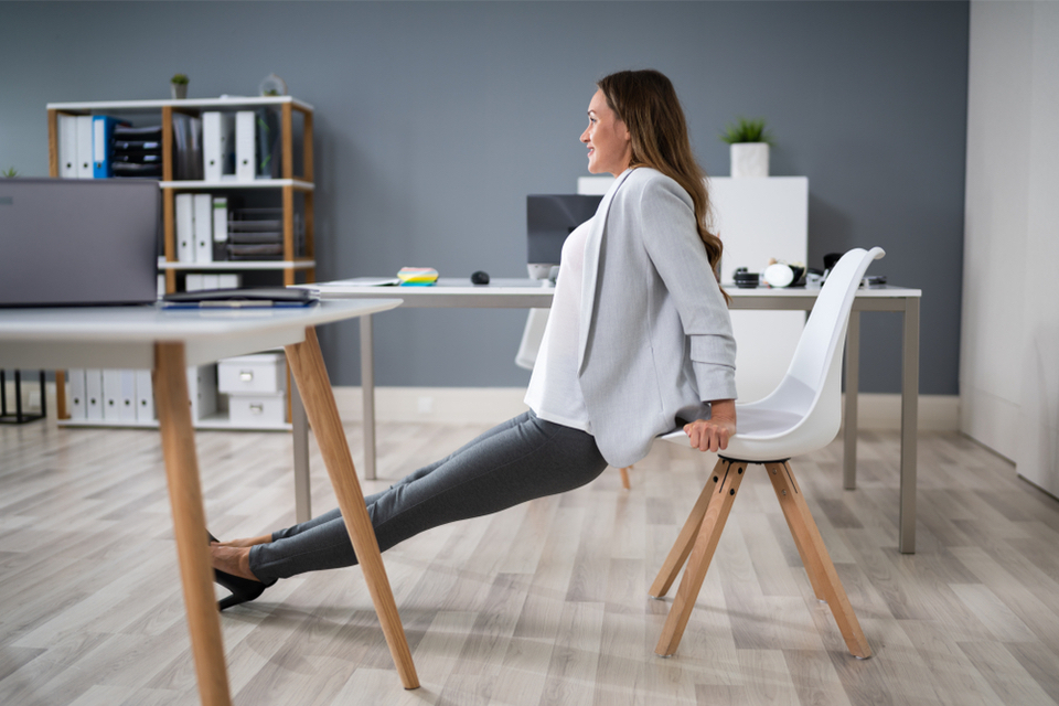 Woman in office doing tricep dip on her chair 