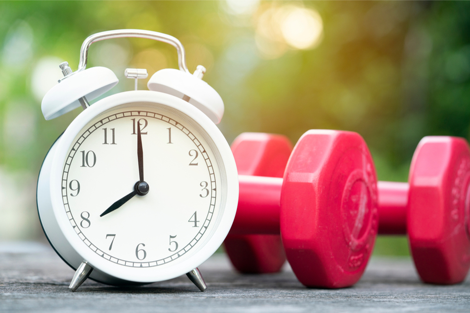 Analog clock next to two dumbbells