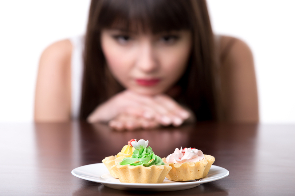 Woman staring at a plate of cupcakes