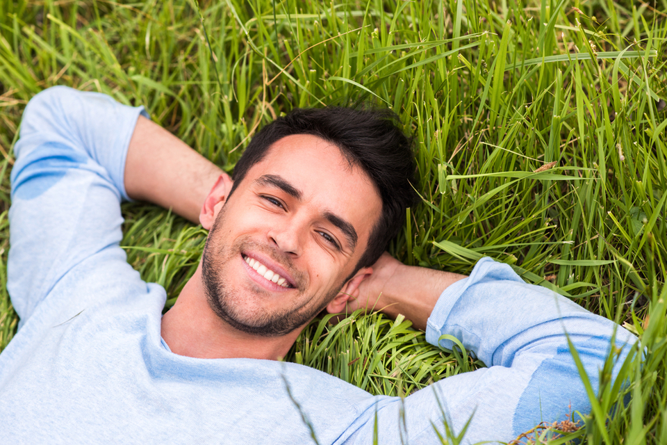 Close up of man smiling while laying in a bed of grass