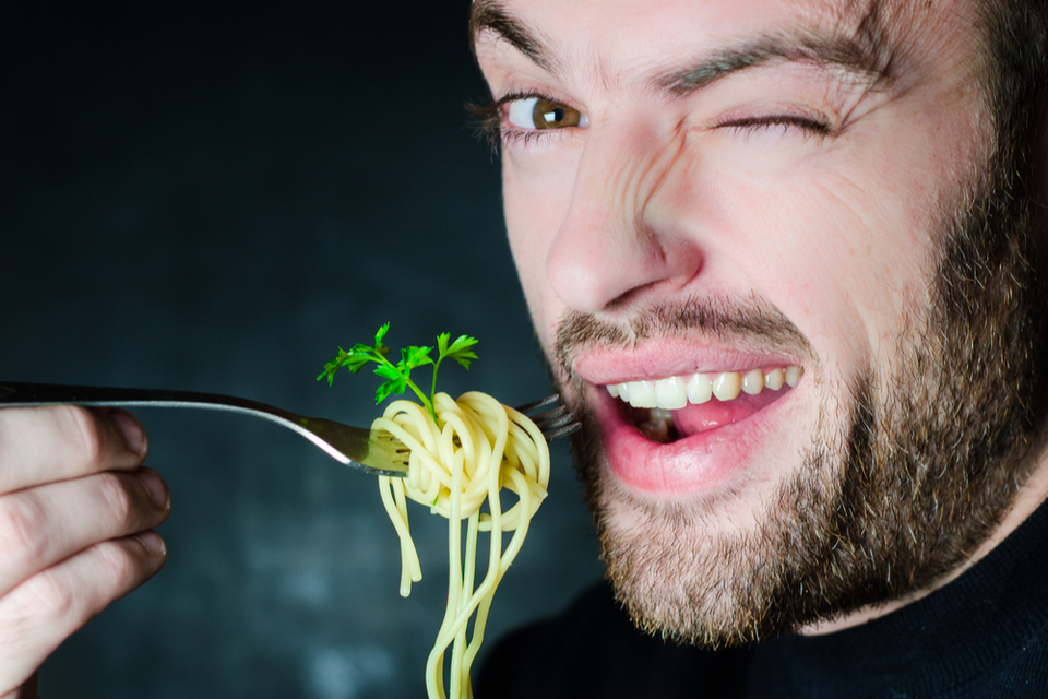 Man winking with a fork full of pasta close to his face