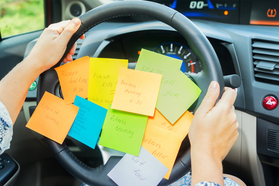 hands on a steering wheel covered in sticky notes with reminders