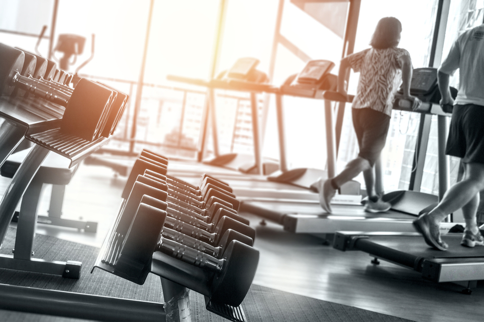 Close up of dumbbells with treadmills in the back