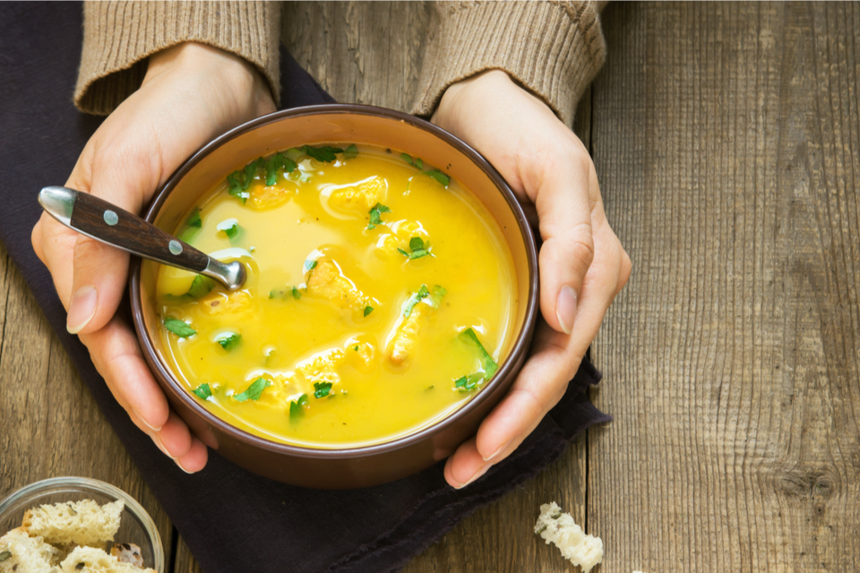 Close up of hands holding a bowl of soup