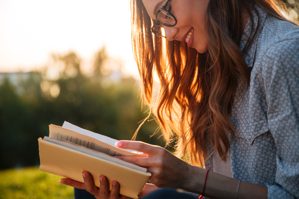 Woman happily reading a book outside