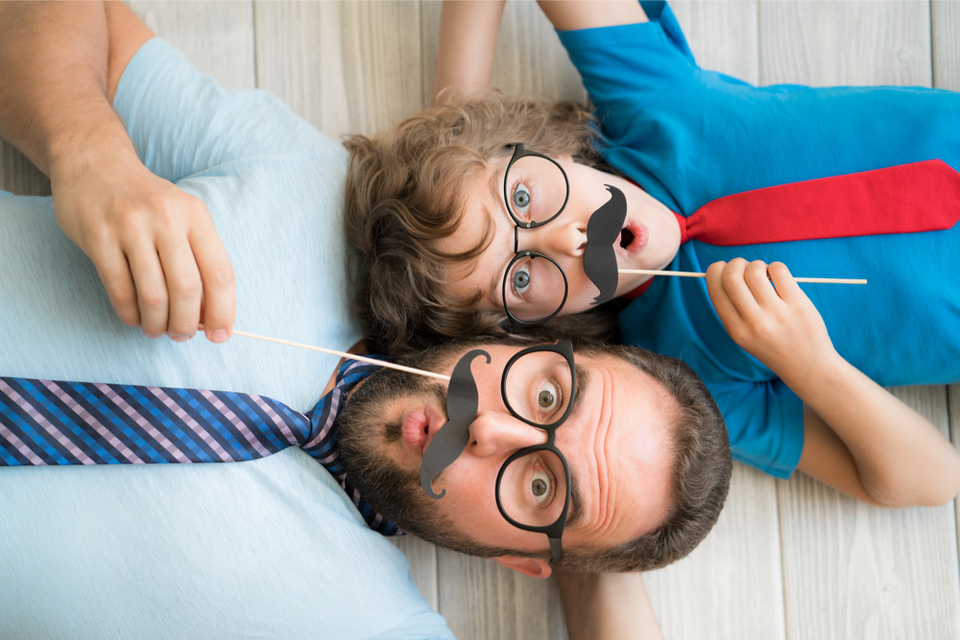 Man and boy holding paper mustache over their upper lips