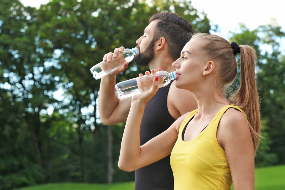 Man and woman standing side by side while drinking water