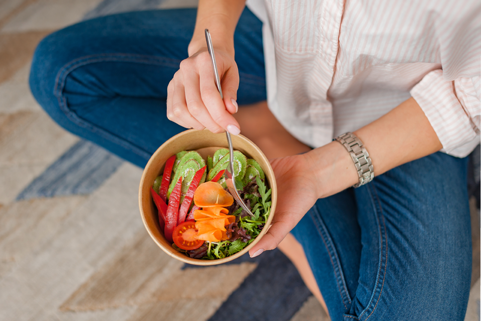 Photo of woman sitting cross legged holding a nutritious meal.