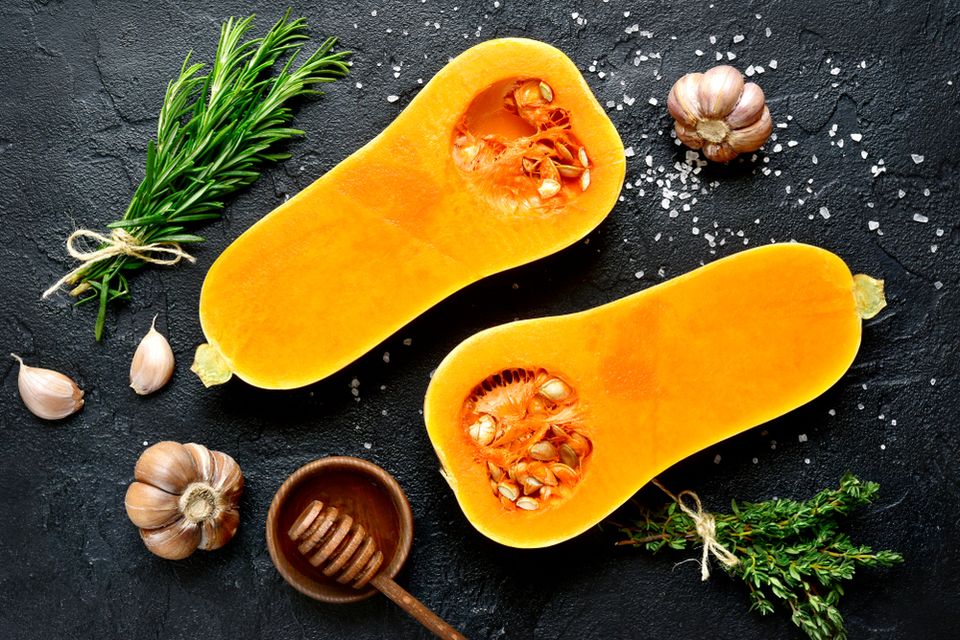 Overhead view of a squash cut in half surrounded by salt and herbs