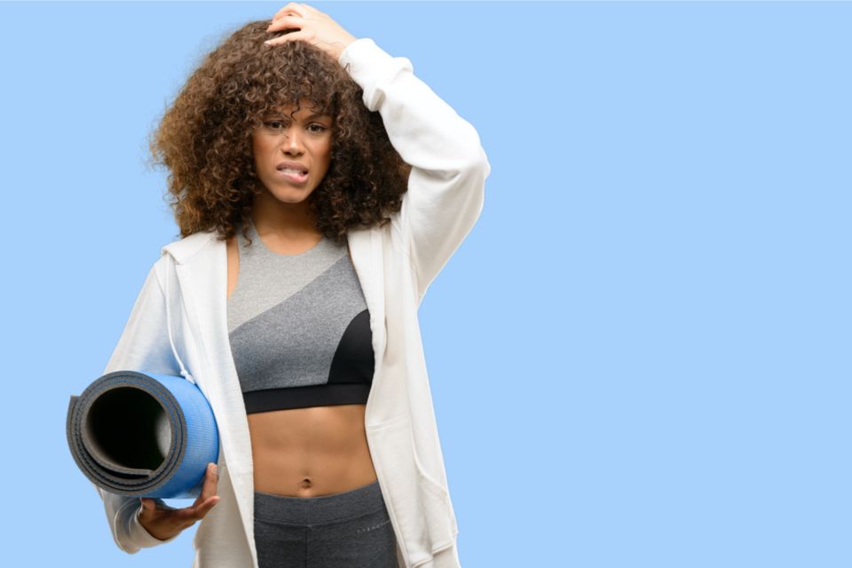 Confused Woman in workout attire holding her head