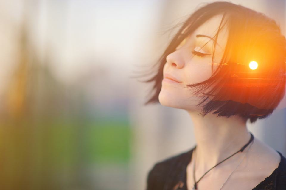 Woman meditating with a sunset overlay on her head