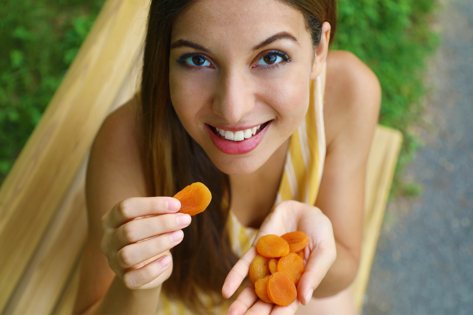 A woman holding slickes of fruit in her hand