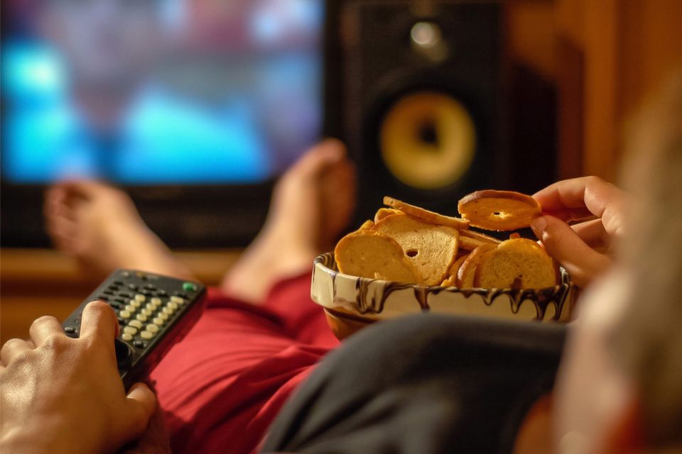 Close up of person laying back , watching tv and eating a snack