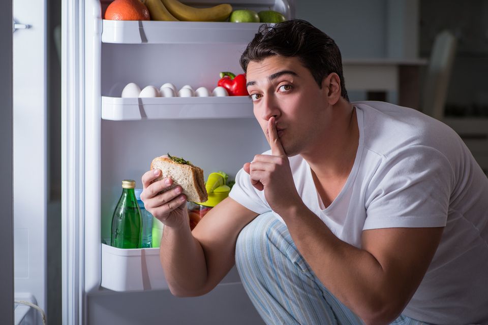 Man sneaking a sandwhich from a fridge late at night