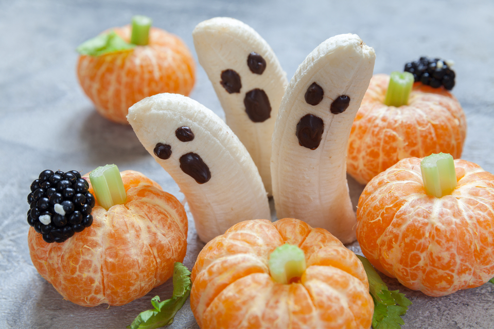 Bananas decorated to look like ghosts with peeled oranges decorated to look like pumpkins